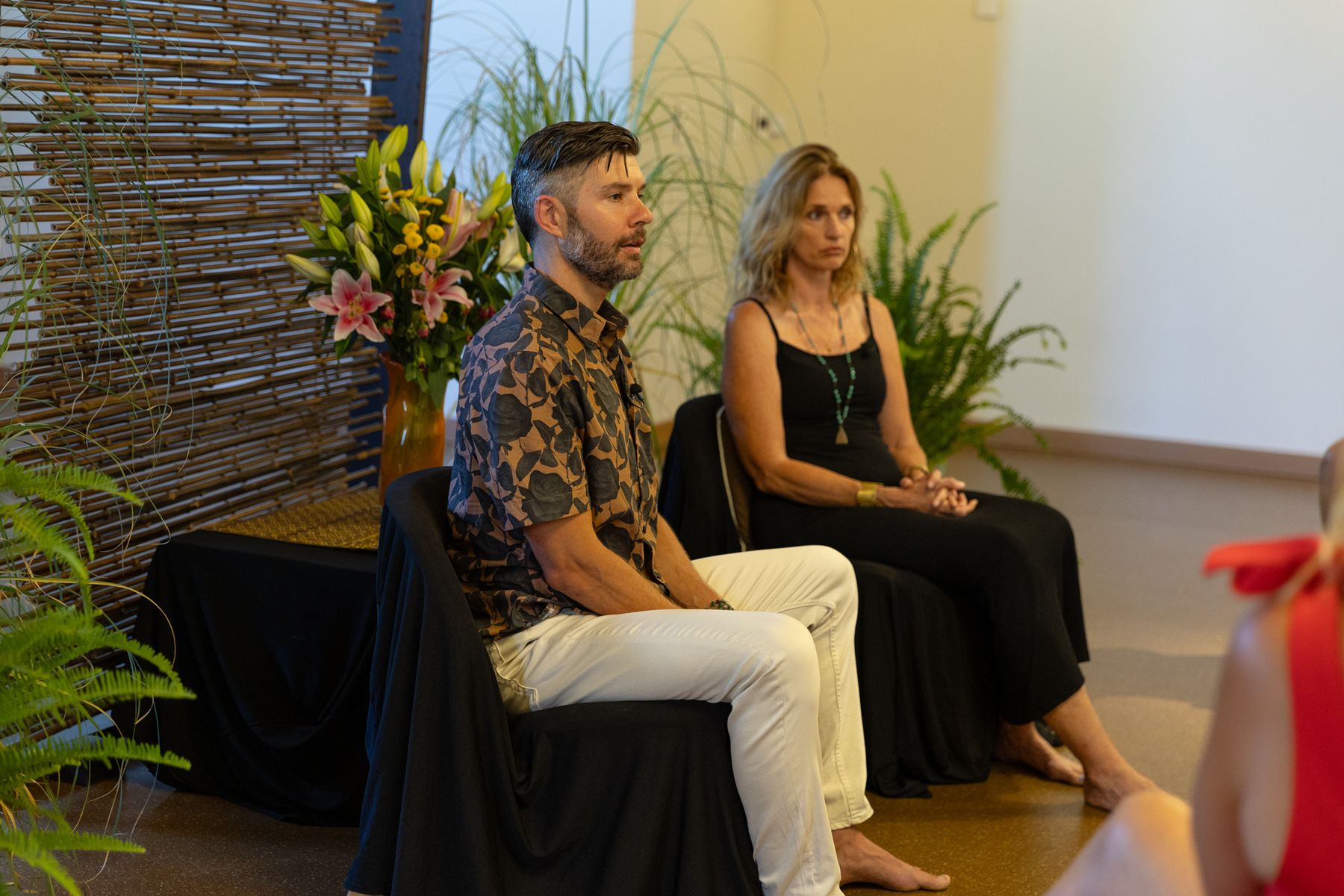 Option C: Sarah and Travis seated in front of the room, wider view.