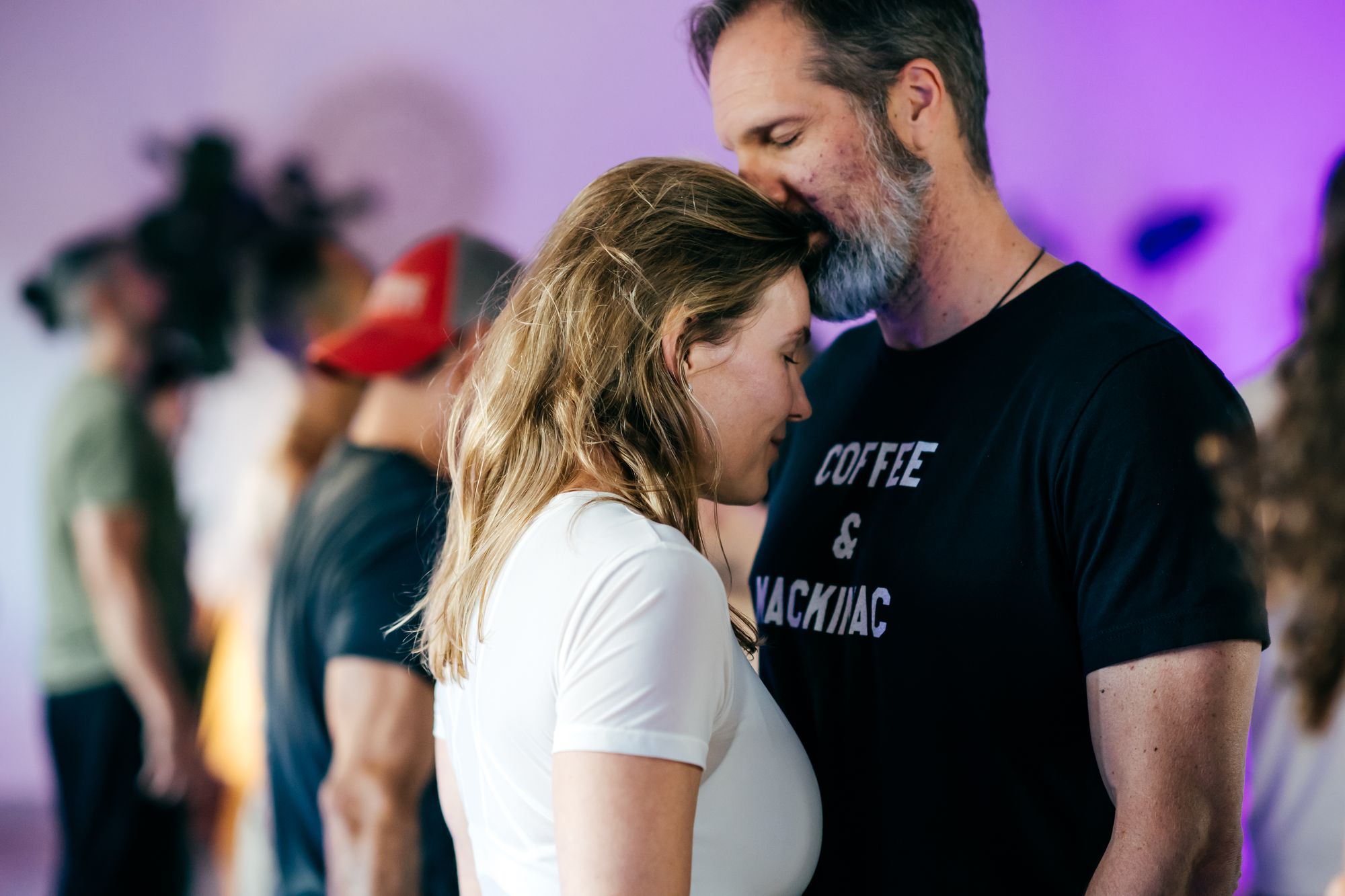 A man resting his forehead against his partner’s head during a couples practice.