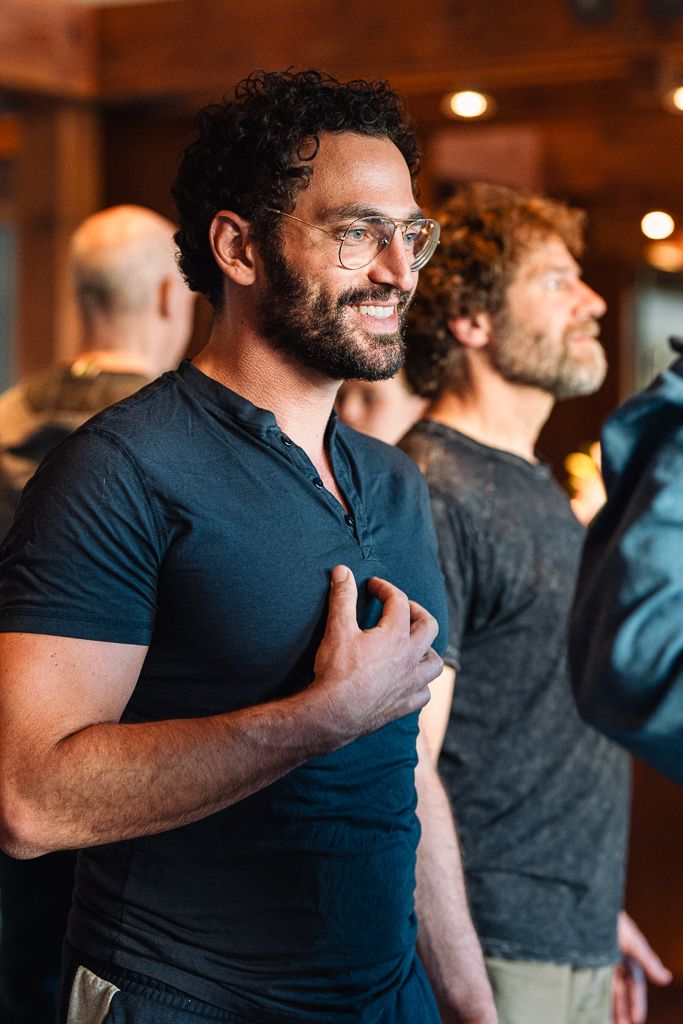 A man smiling with his hand on his heart during a couples workshop.