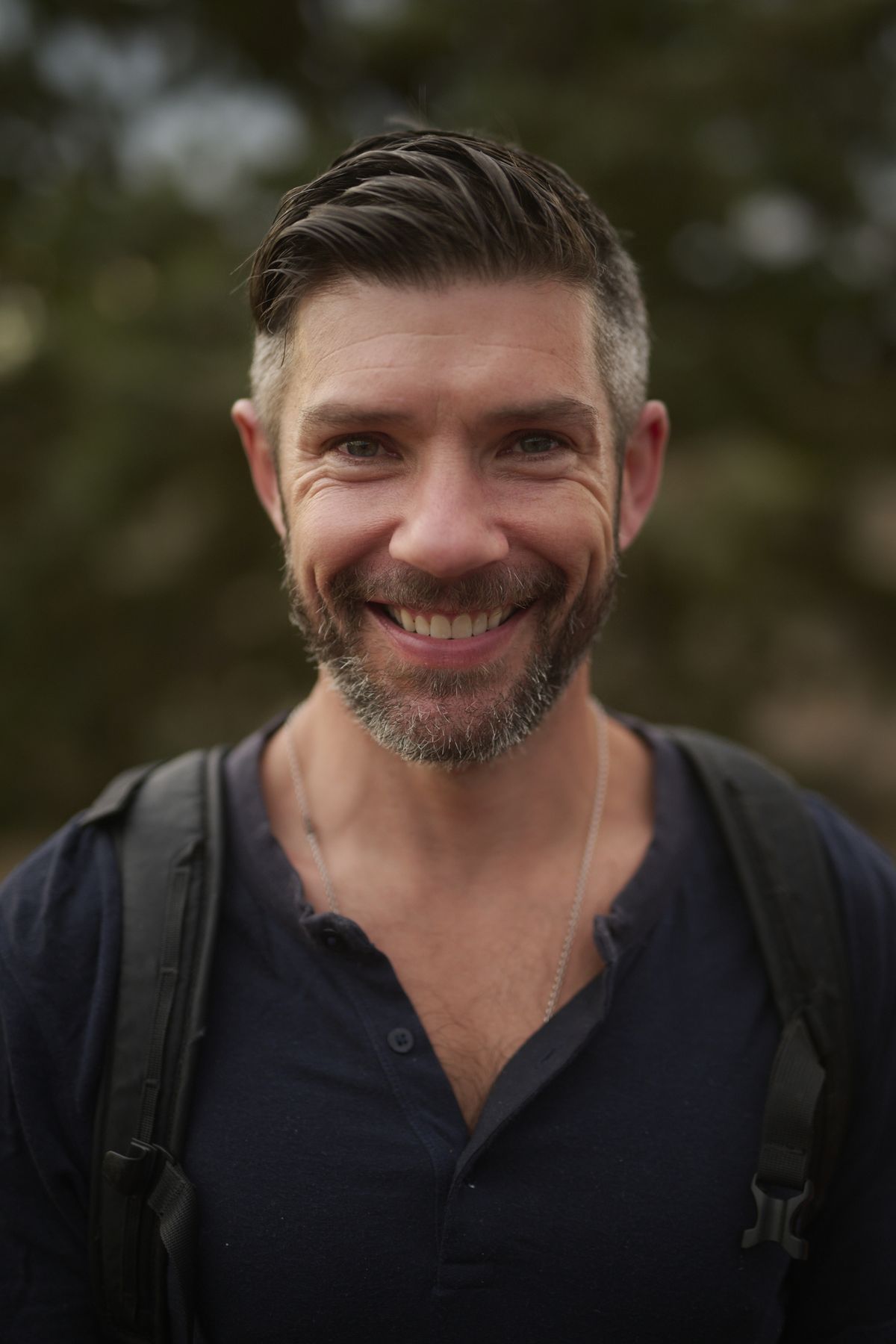 Option A, on the page now: Travis smiling outdoors.